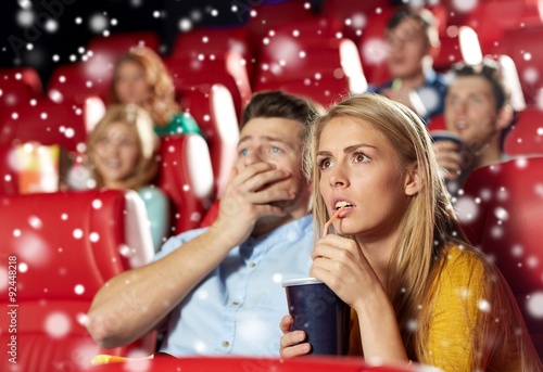 friends or couple watching horror movie in theater