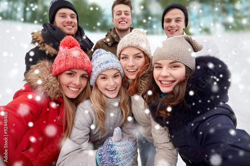 group of smiling friends taking selfie outdoors