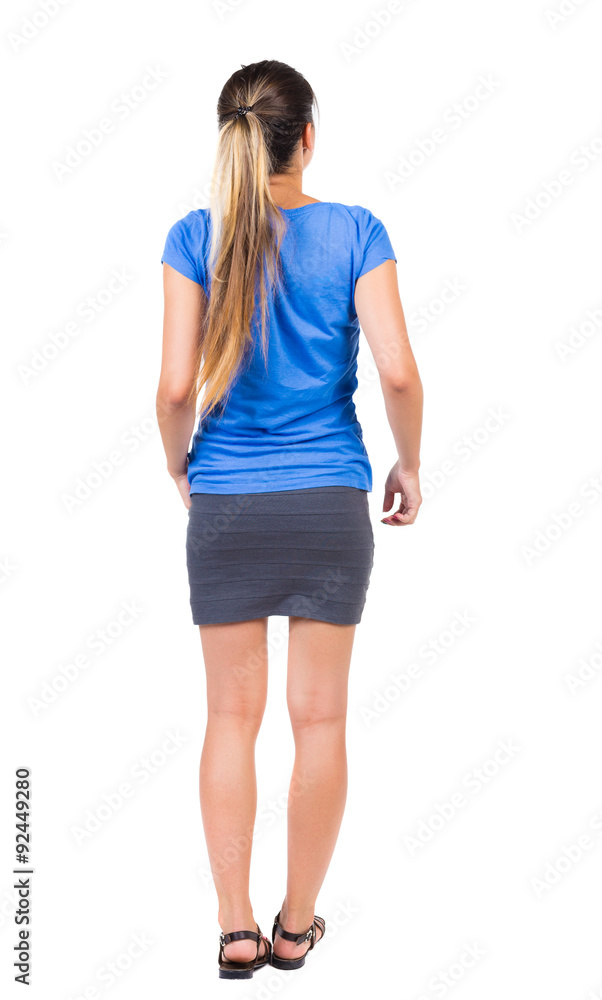 back view of standing young beautiful woman. girl watching. Rear view people collection. backside view of person. Isolated over white background. Girl in a gray skirt and blue shirt stands back view of standing young beautiful woman. girl watching. Rear view people collection. backside view of person. Isolated over white background. Girl in a gray skirt and blue shirt stands
