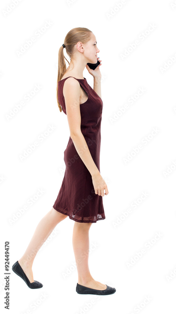 a side view of a woman walking with a mobile phone. a side view of a woman walking with a mobile phone.