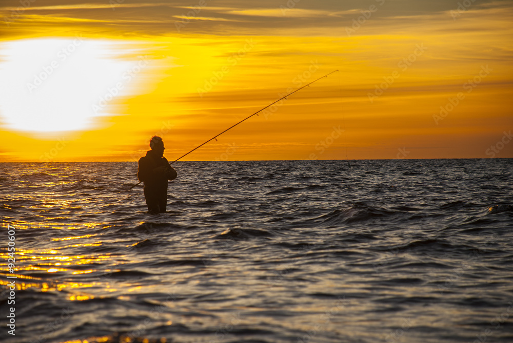 Angler fishing at the coast in an Autumn sunset