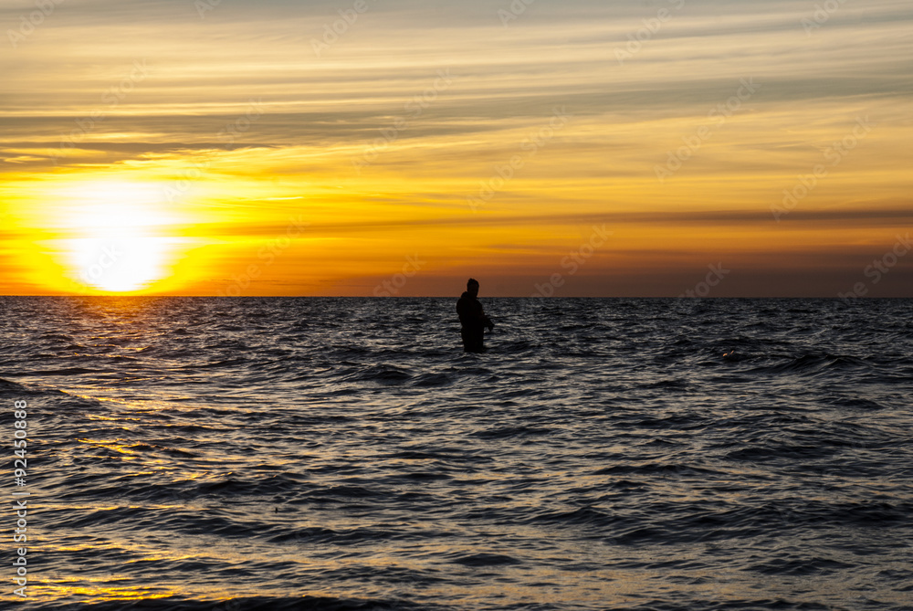 Angler fishing at the coast in an Autumn sunset