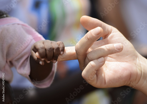 Black Baby and White woman holds hands with a little baby native African girl, in Bamako, Mali. Peace on earth symbol. A beautiful shot with lots of possible background symbols. No to Racism! photo