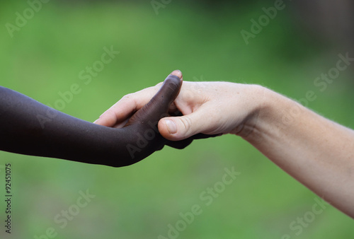 African Symbol Of Love - Black and White Holding Hands. African Peace Symbol. White woman holds hands with a little native African girl, in Bamako, Mali. A black child and a white woman hold hands. © Riccardo Niels Mayer