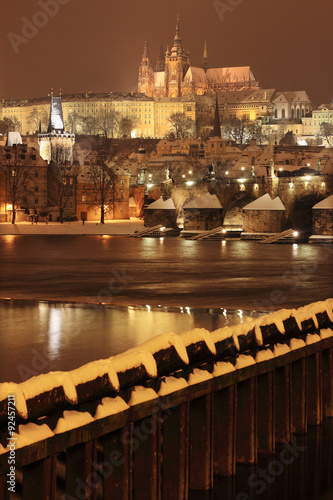 Night romantic colorful snowy Prague gothic Castle with Charles Bridge, Czech Republic