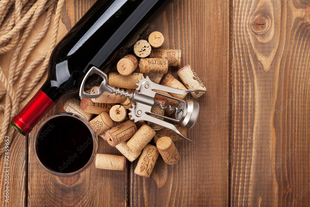 Glass of red wine, bottle and corkscrew on rustic wooden table Glass of red wine, bottle and corkscrew on rustic wooden table