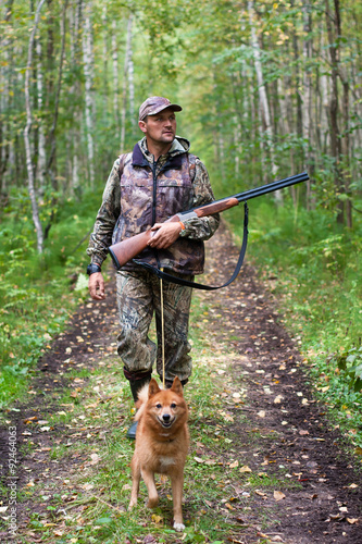 hunter in camouflage with dog on the forest road