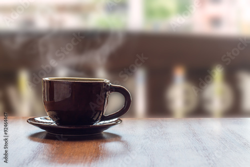 coffee cup on wood table with blur background in cafe.