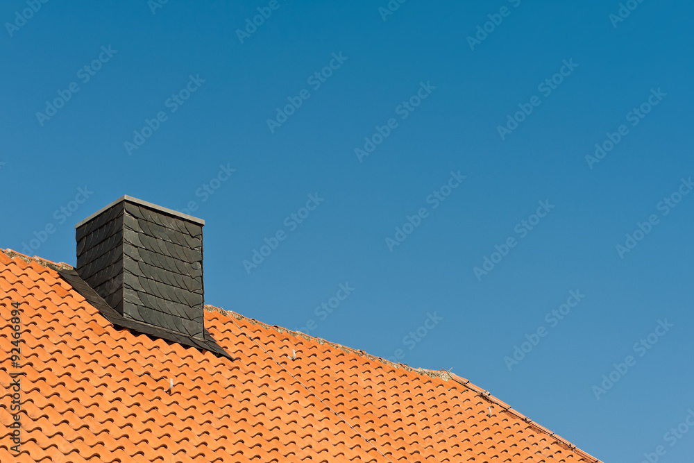 Ein mit Schiefer verkleideter Schornstein in einem Tonziegeldach Ein mit Schiefer verkleideter Schornstein in einem Tonziegeldach