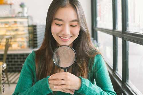 Smiling beautiful teenage asian girl with magnify search somethi photo