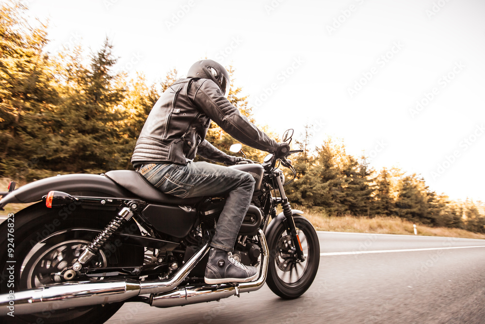 Obraz premium Siedzenie człowieka na motocyklu na drodze w lesie.