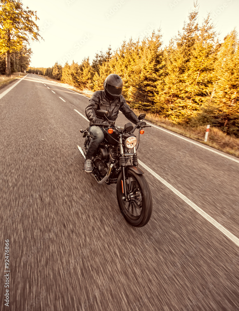 Obraz premium Siedzenie człowieka na motocyklu na drodze w lesie.