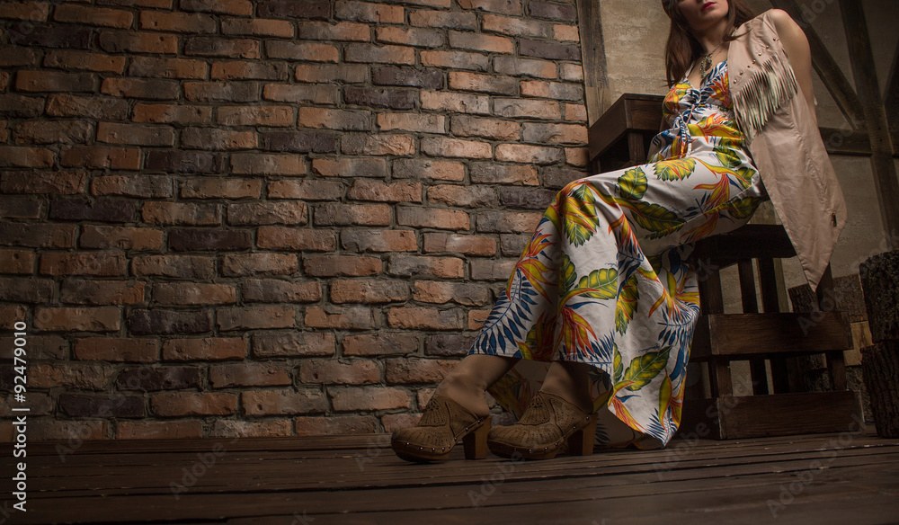 Naklejka premium young sensual woman sitting on chair on old brick wall backgroun