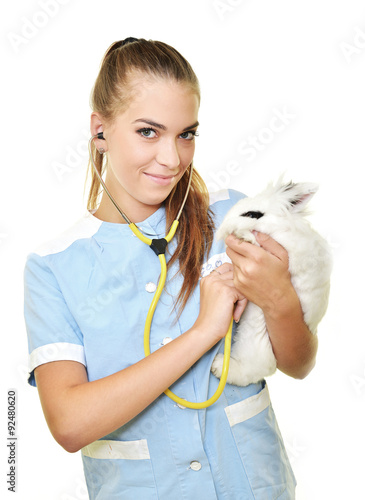 Smiling vet holding up and examining cute brown rabbit at pets' clinic. photo