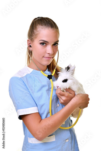 Smiling vet holding up and examining cute brown rabbit at pets' clinic. photo