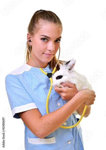 Smiling vet holding up and examining cute brown rabbit at pets' clinic. photo