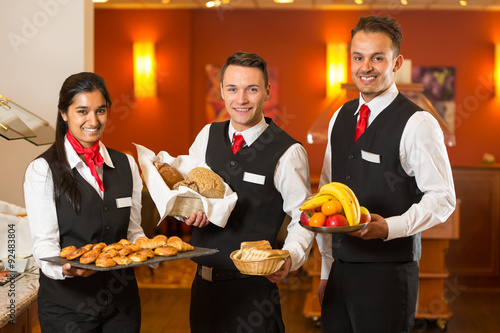 Waitress and waiters posing with food at buffet in a restaurant