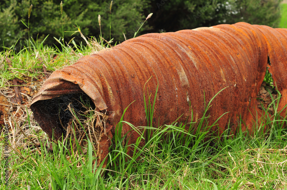 Industrial waste – rusty iron big bore pipe in the fresh green grass reminding of the recent human presence. Industrial waste – rusty iron big bore pipe in the fresh green grass reminding of the recent human presence.