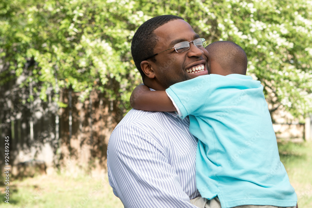 African American father and son hugging and laughing. African American father and son hugging and laughing.