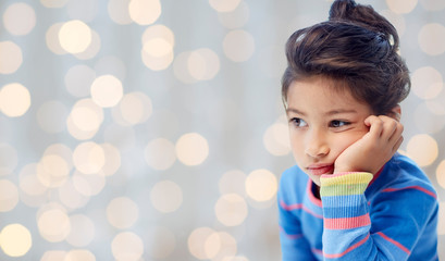 sad little girl over holidays lights background