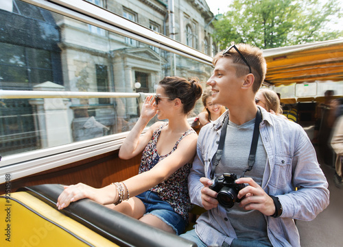 smiling couple with camera traveling by tour bus photo