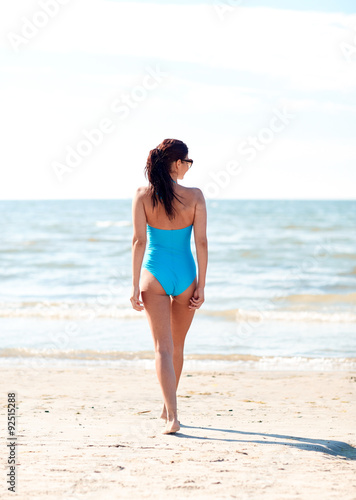 young woman in swimsuit walking on beach © Syda Productions
