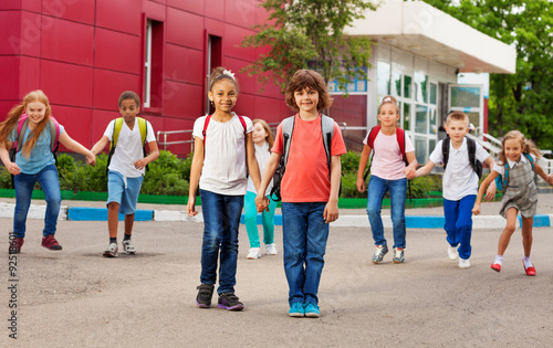 Rows of kids with rucksacks near school walking