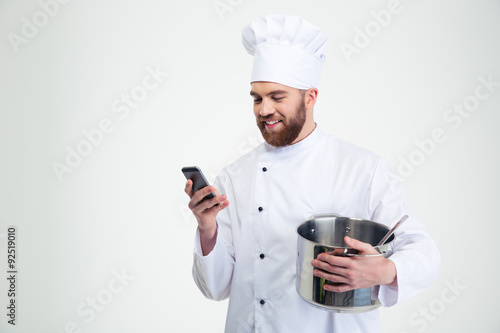 Male chef cook holding pot and using smartphone