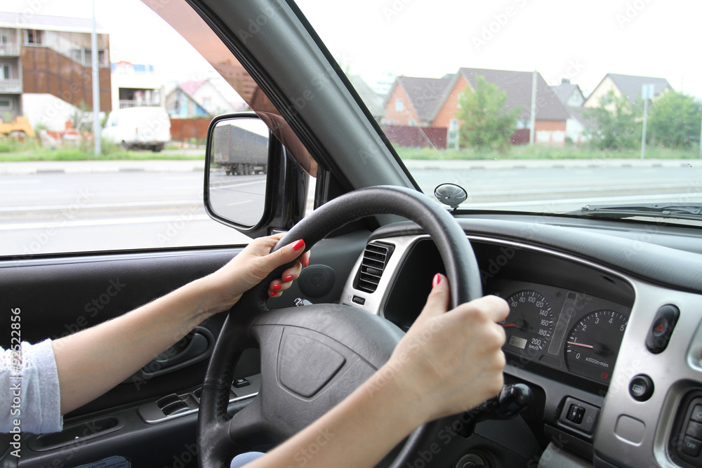 Female hands on  a car wheel