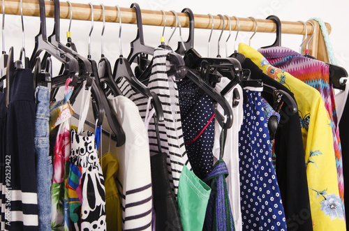 Close up on colorful clothes on hangers in a store. Clothes and accessories hanging on a rack nicely arranged.