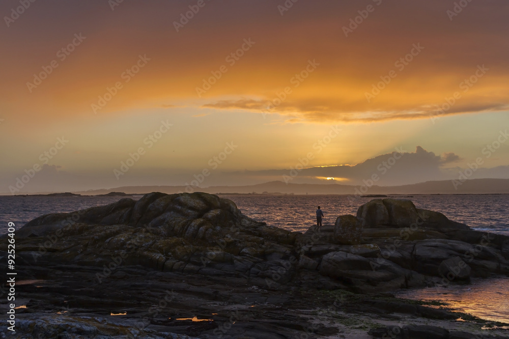 Angler on the rocks at dusk