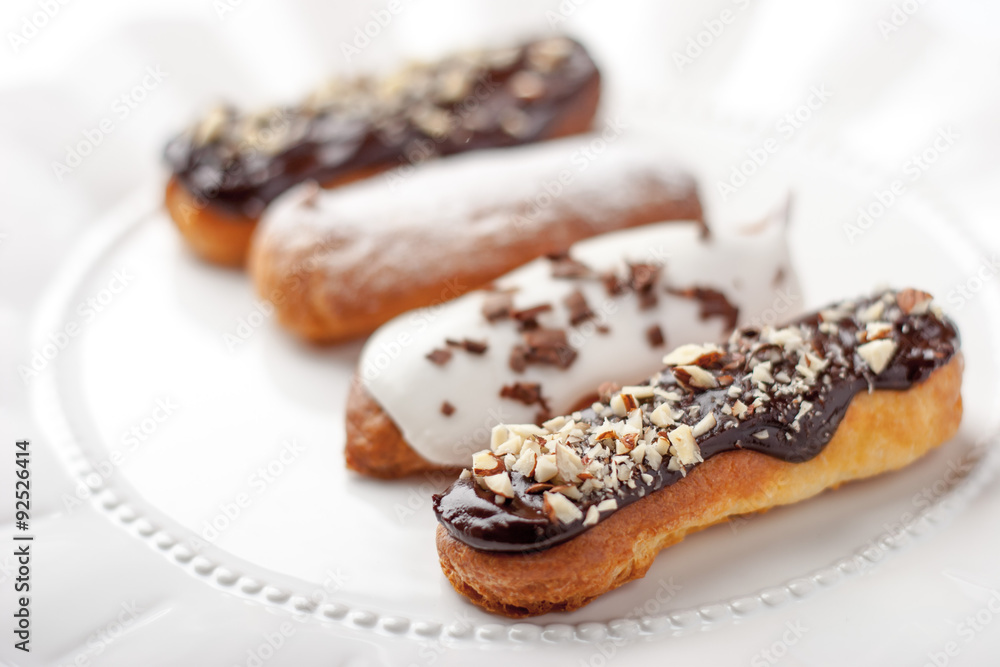 Chocolate and vanilla eclairs on the ceramic plate Chocolate and vanilla eclairs on the ceramic plate