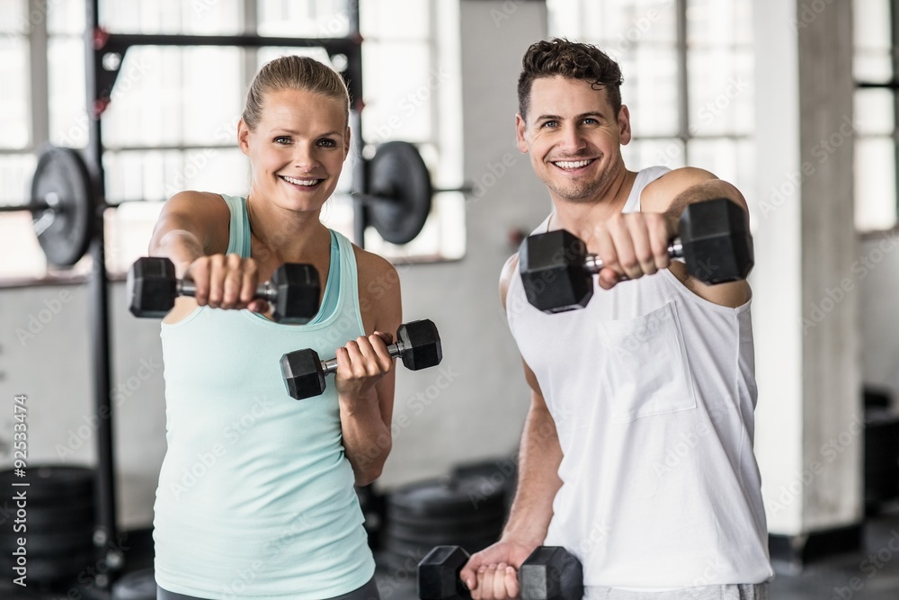 couple exercising with dumbbells in gym couple exercising with dumbbells in gym