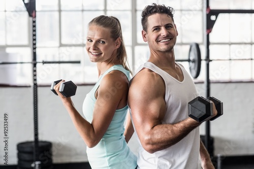 Smiling couple exercising with dumbbells 