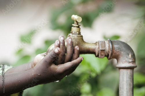 Poor African black boy holding hands under a tap. Water scarcity problems concern the inadequate access to safe drinking water. 1 billion people in the developing world don t have access to it.