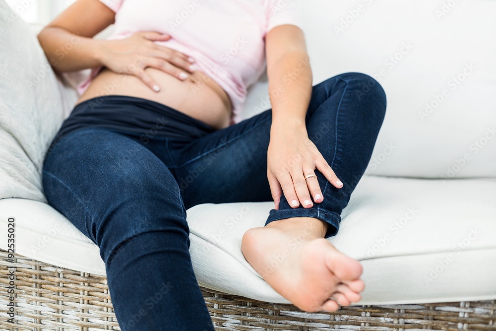 Low section of pregnant woman touching belly