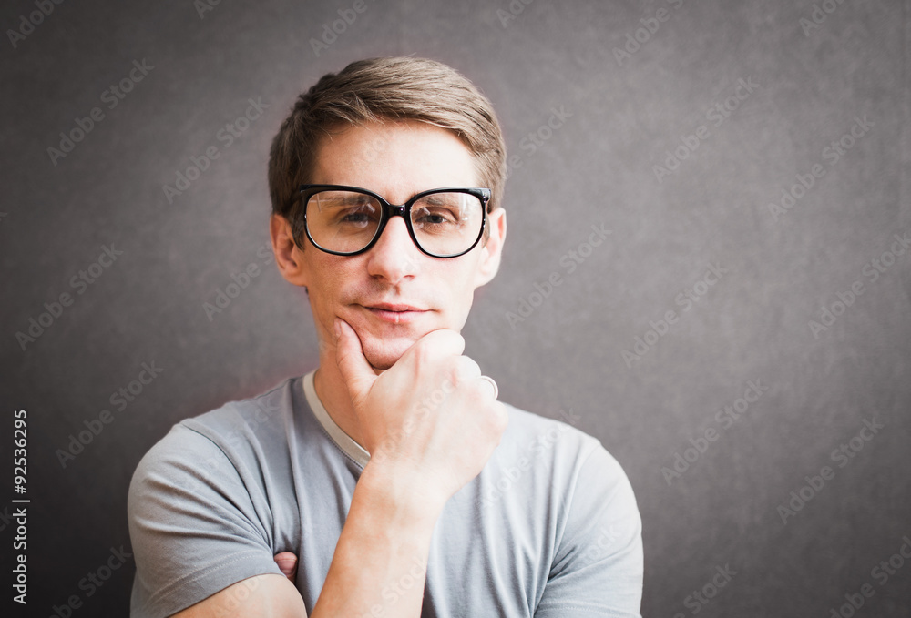 Portrait of a man with eyeglasses standing against gray wall, h Portrait of a man with eyeglasses standing against gray wall, h