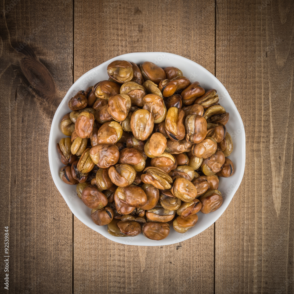 Broad beans in a white bowl on wooden boards top view Broad beans in a white bowl on wooden boards top view