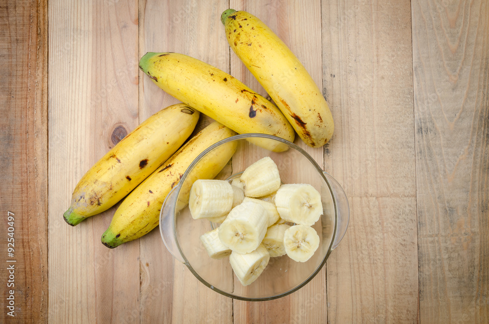 Top view banch of bananas and a sliced banana in a glass bowl o Top view banch of bananas and a sliced banana in a glass bowl o