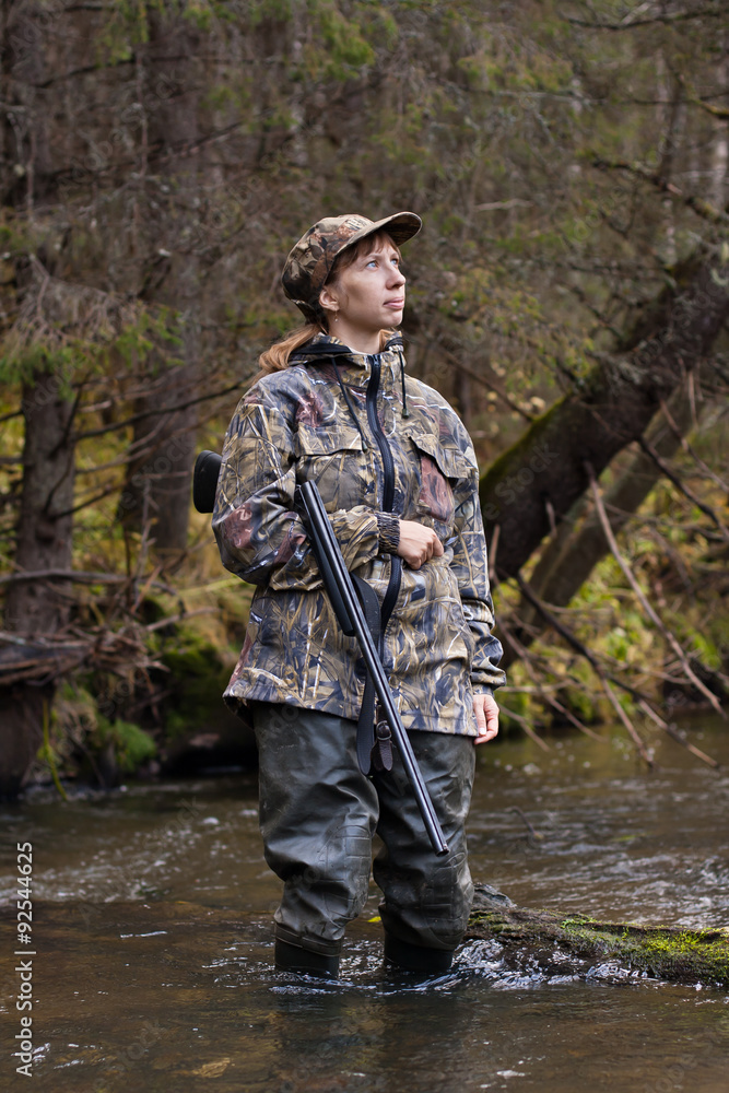 Woman hunter in camouflage on the river