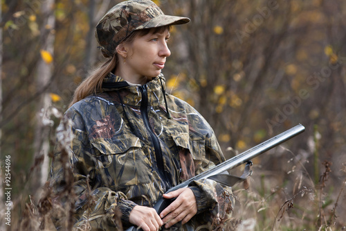 Woman hunter with gun in autumn forest