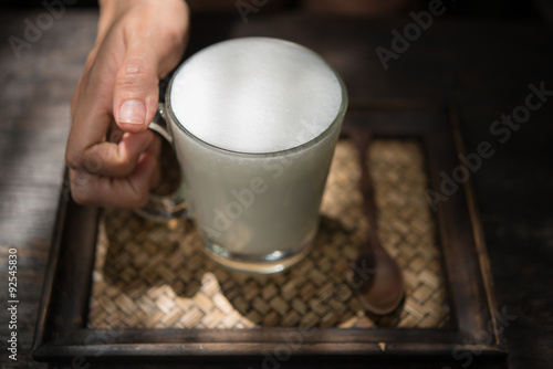 Woman holding a glass of hot milk relax in the cafe.