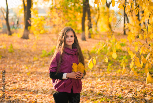 Smiling girl with autumn maple leaves at fall outdoors