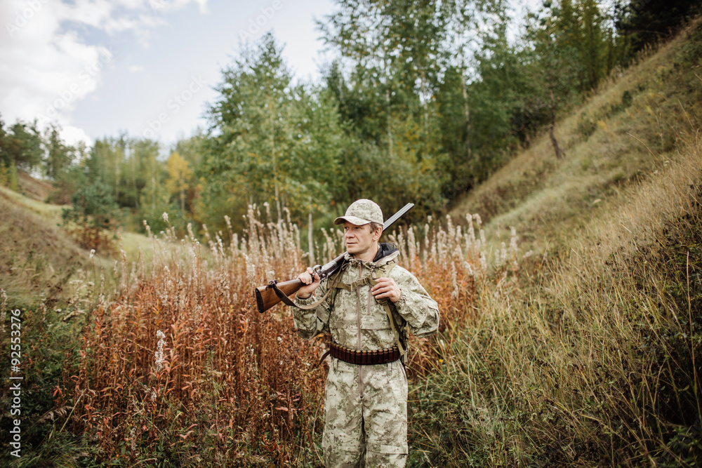 man hunter with shotgun in forest