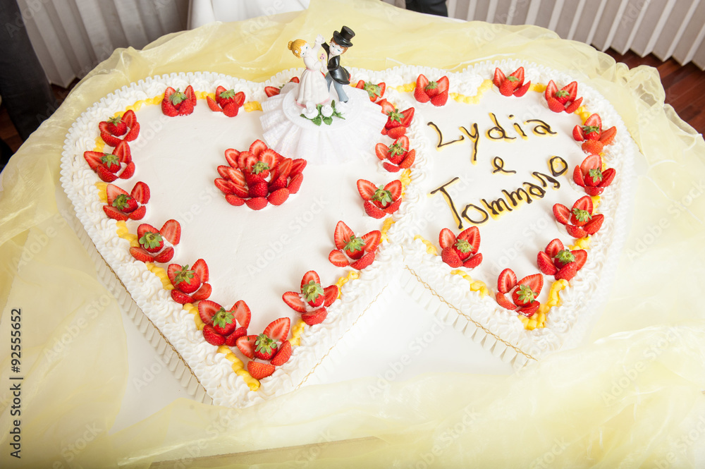 Torta di matrimonio a forma di cuore con panna e fragole sul tavolo Torta di matrimonio a forma di cuore con panna e fragole sul tavolo
