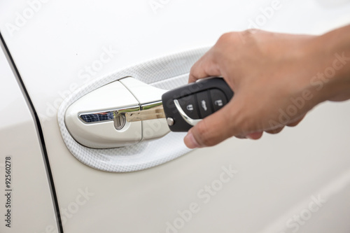 Closeup of a woman's hand inserting a key into the door lock of a white car.(focus keyhole)