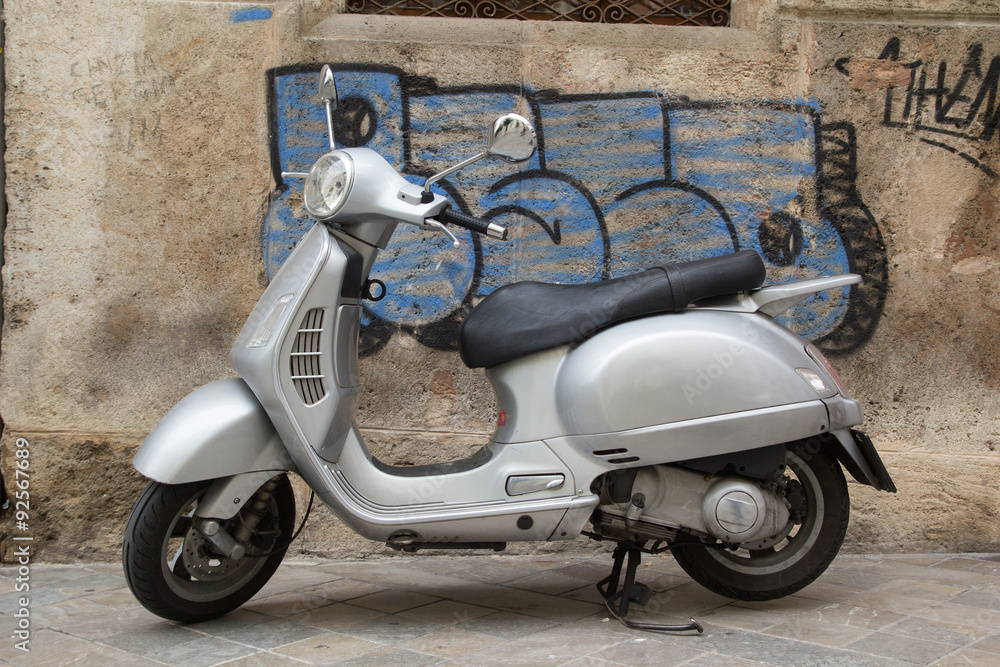 Silver Scooter parked on the sidewalk in Europe.