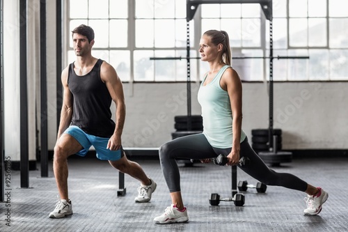 Male trainor with woman using dumbbells exercising 