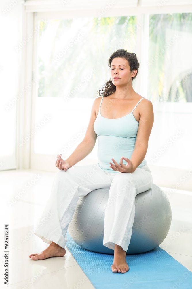 Peaceful blonde pregnant woman sitting on exercise ball