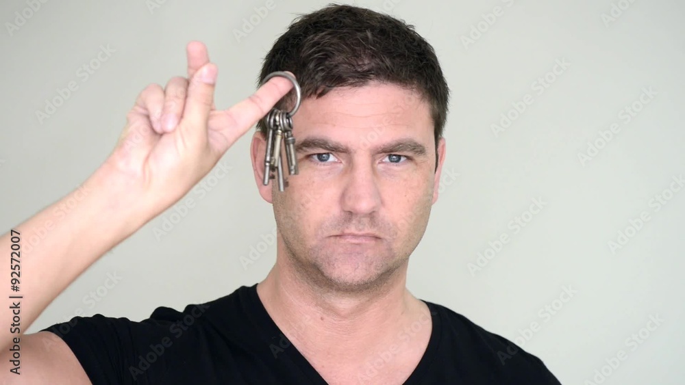 Serious and determined man holding set of keys, looking at camera. Serious and determined man holding set of keys, looking at camera.